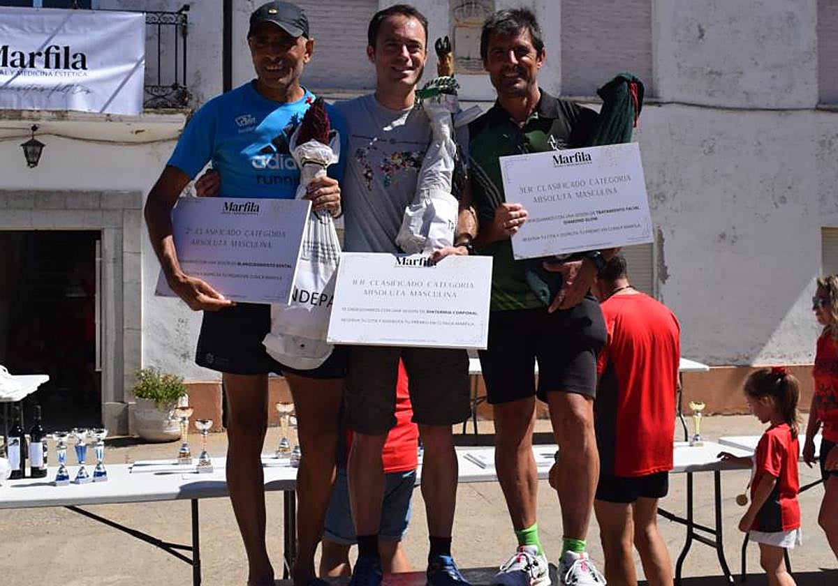 Los tres primeros clasificados posan en el podio con sus trofeos.