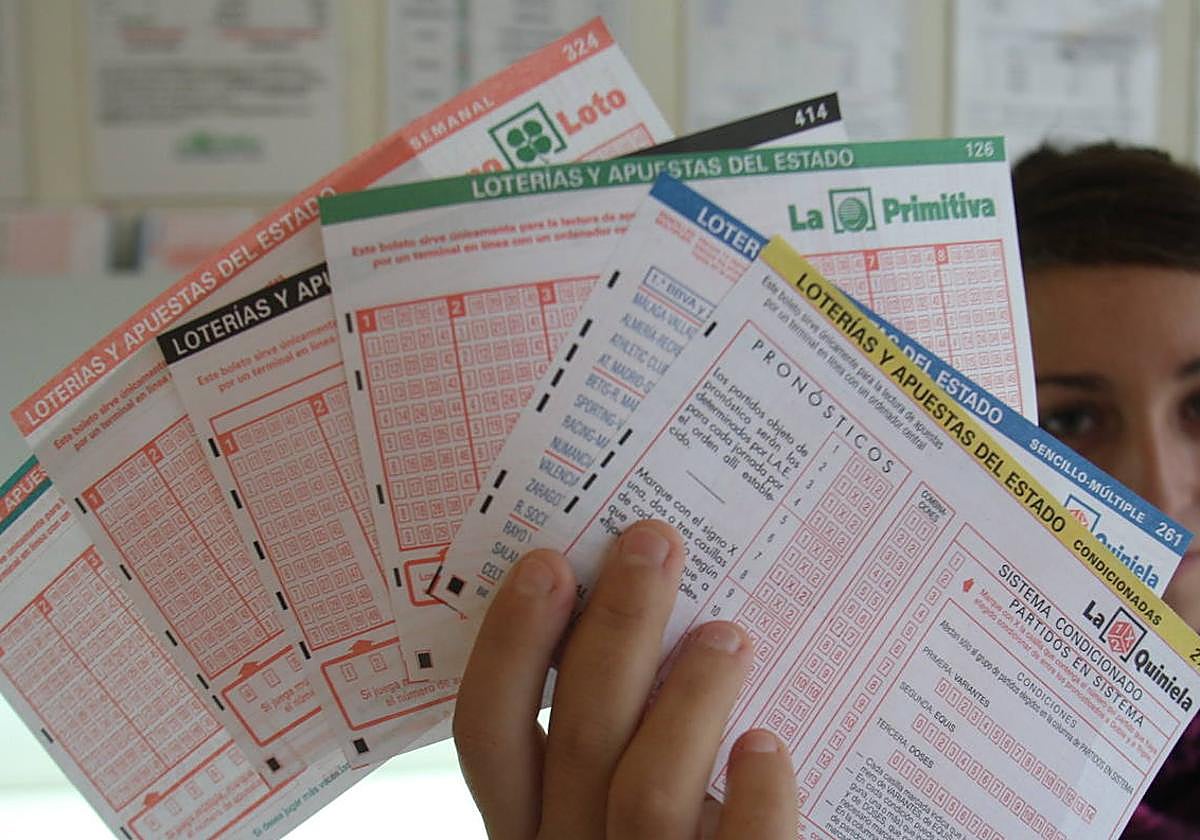 Una joven muestra boletos de lotería y quinielas en una administración, en una imagen de archivo.