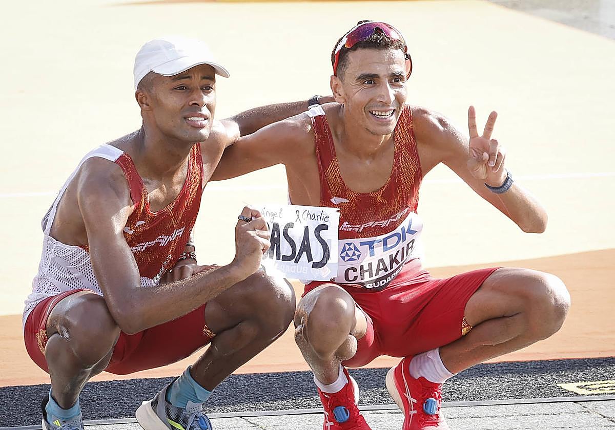 Los atletas españoles Tariku Novales (i) e Ibrahim Chakir durante la maratón, este domingo en el Campeonato del Mundo de Atletismo de Budapest. En la imagen, mostrando un cartel en recuerdo del fisioterapeuta de la Federación Española, Ángel Basas, fallecido recientemente junto a su hijo en un accidente.