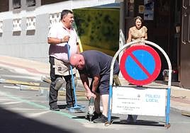 Una persona taladra el suelo para instalar los postes que delimiten la zona de terrazas.