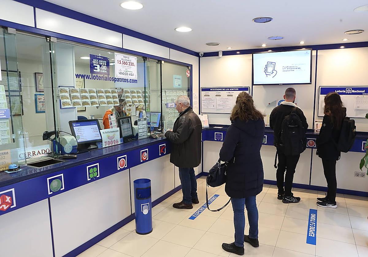 Varias personas esperan en una Administración de Lotería.