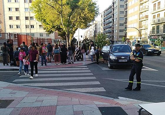 Un agente de la Policía Local vigila el aparcamiento a la puerta de un colegio.