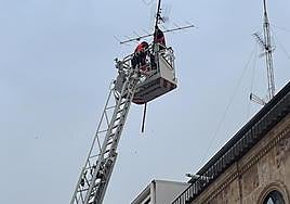 Los bomberos retiran una antena en un edificio del centro de al ciudad.