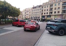 Calle peatonal llena de coches en el acceso a un parking.