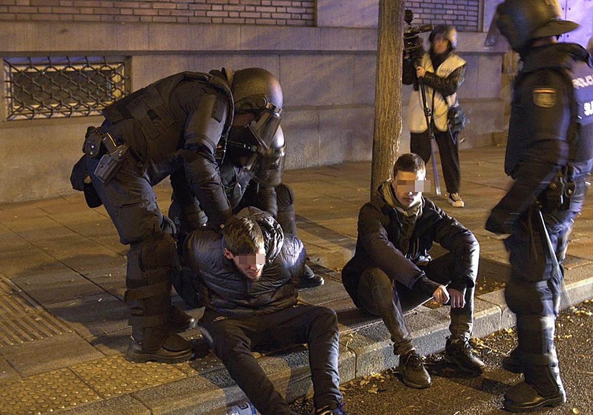 Efectivos de la UIP de la Policía detienen ayer a dos manifestantes cerca de la sede del PSOE en la calle Ferraz.