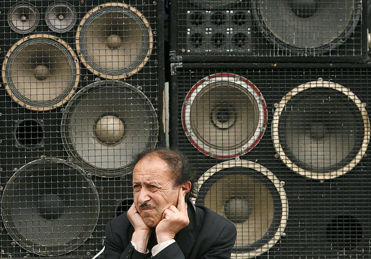 Un hombre se lleva las manos a los oídos delante de unos altavoces.