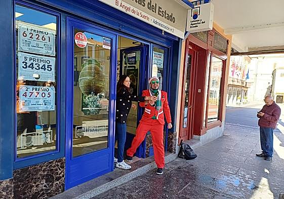 La responsable de la administración de Peñaranda de Bracamonte con una botella de cava, junto a un hombre disfrazado de Papá Noel.