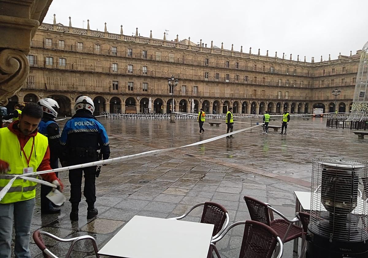 Operarios y Policía Local preparan el paso de la San Silvestre Salmantina por la Plaza Mayor.