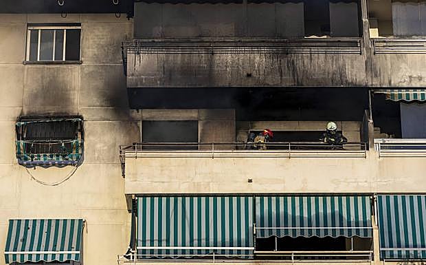Imagen principal - En la imagen superior, los bomberos en la terraza del piso donde comenzó el fuego; debajo, vista de la fachada del edificio de Fuengirola en la que se observa como el incendio terminó dañando parte de los pisos superiores; por último, varios policías vigilan los acceso al lugar de los hechos.
