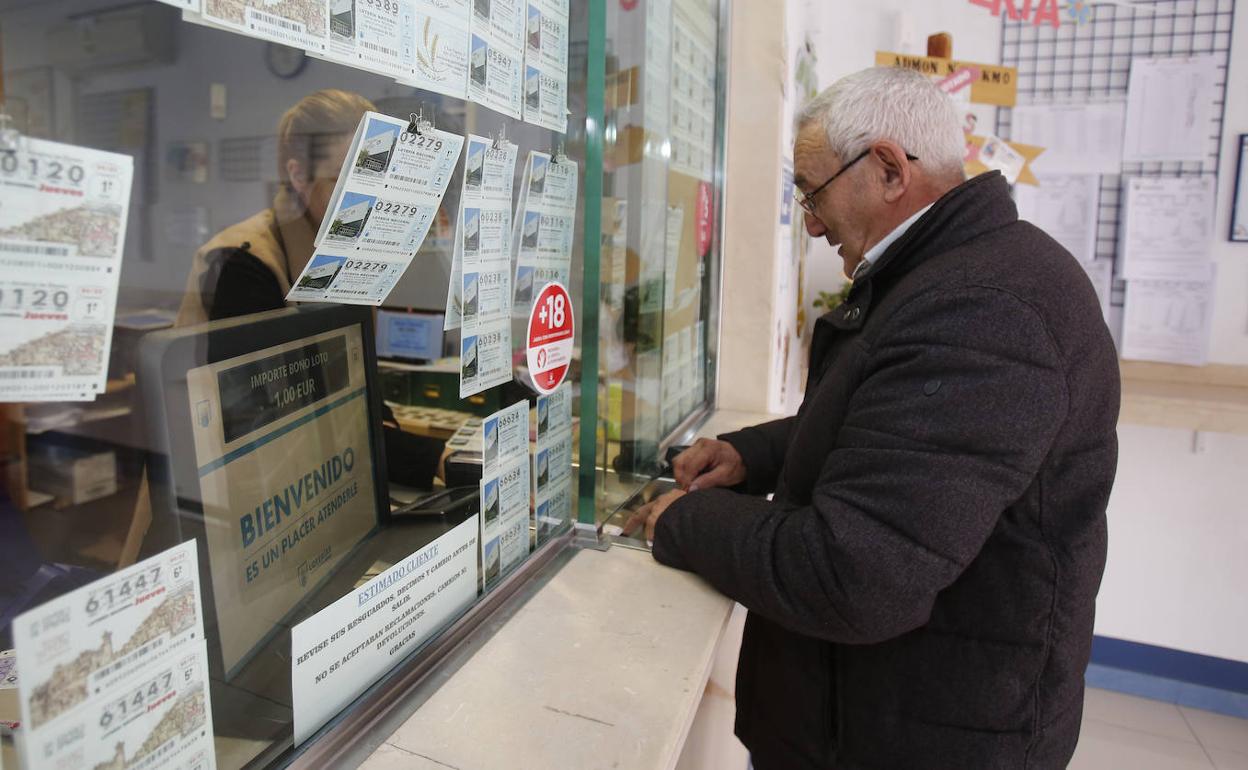 Un hombre compra un décimo en una administración de loterías. 