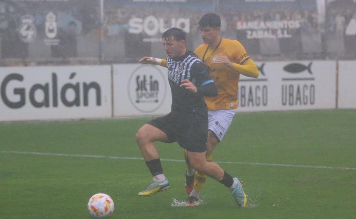 Un jugador de Unionistas disputando la posesión a un jugador de la RB Linense antes de la suspensión del encuentro.