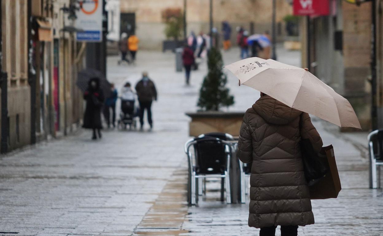 Imagen de archivo de individuos caminando por la calle Zamora de Salamanca en un día de lluvia.