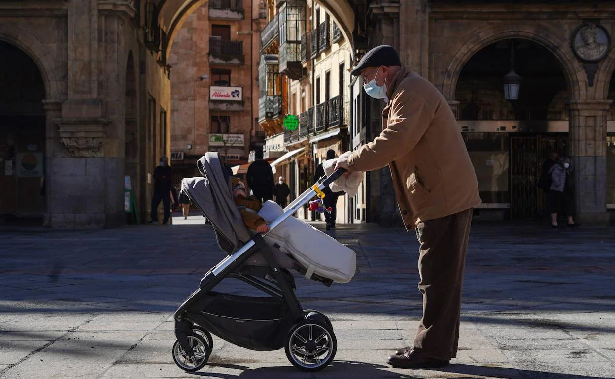 Un abuelo pasea con su nieto por la Plaza Mayor de Salamanca. 