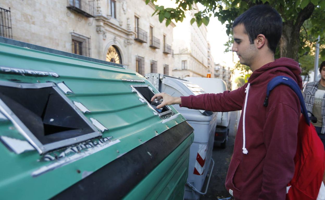 Imagen de archivo de un hombre depositando una botella en un contenedor de vidrio en Salamanca.