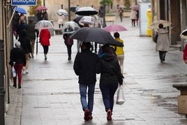 Varias personas pasean por Salamanca con paraguas.
