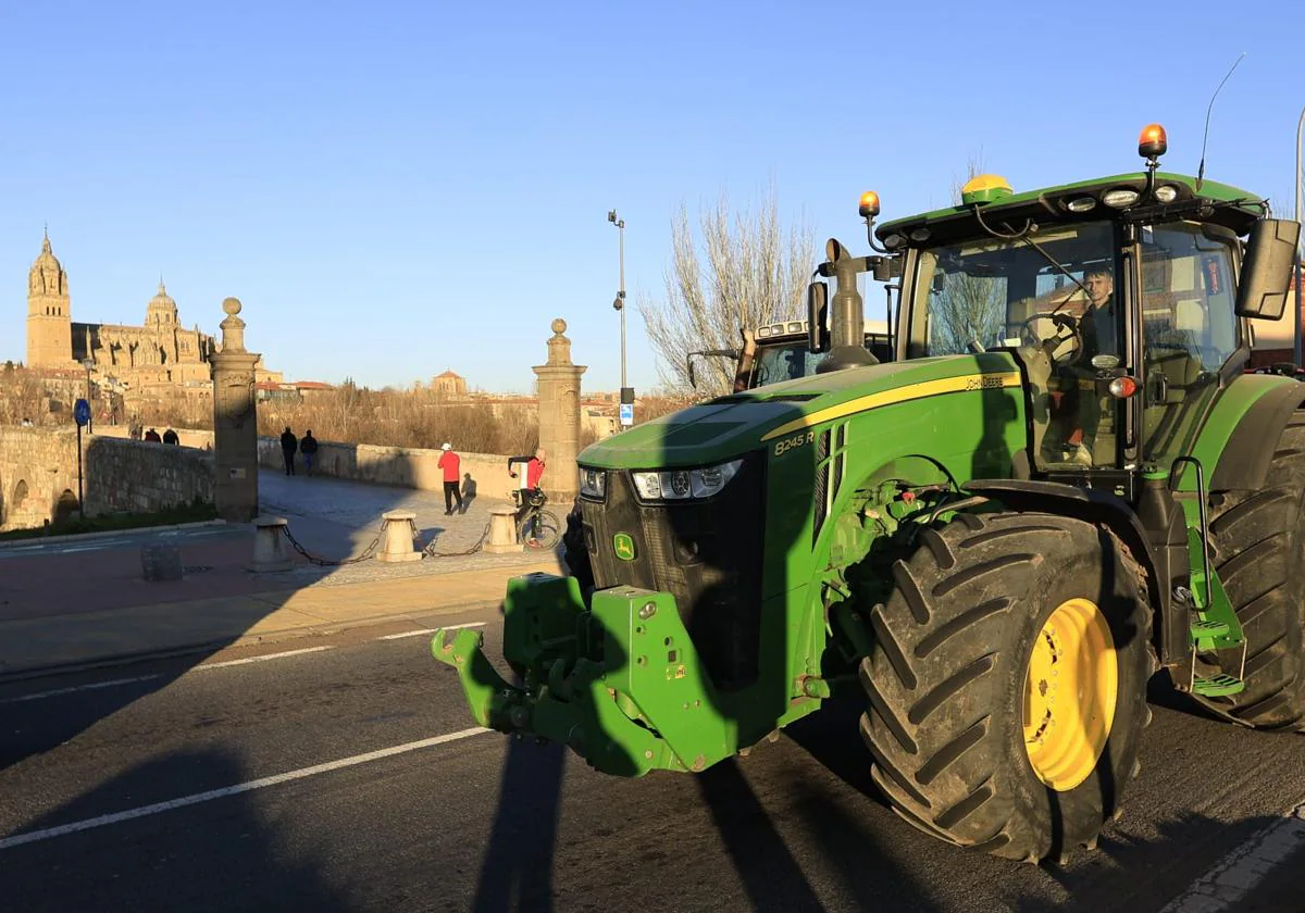 Un tractor este martes a su paso por el puente romano de Salamanca con las catedrales al fondo.