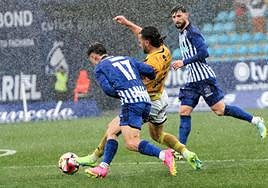 Álvaro disputa un balón a dos jugadores de la Ponferradina bajo un fuerte aguacero.