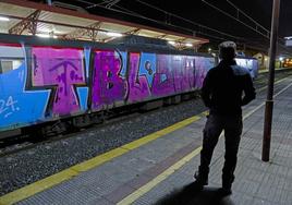 Un hombre observa un tren de Renfe completamente pintado en un acto vandálico.