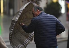 Un hombre trata de protegerse del viento.