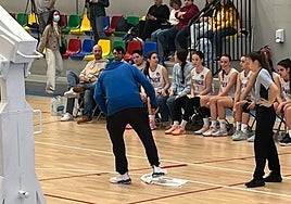 Un entrenador de la cantera de Avenida limpia el agua caída en el parqué durante un día de lluvia en un partido en el Anexo de Würzburg.