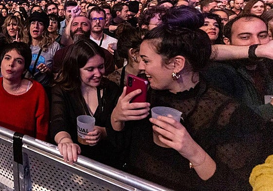 Varias jóvenes, con vasos de plástico durante un concierto.