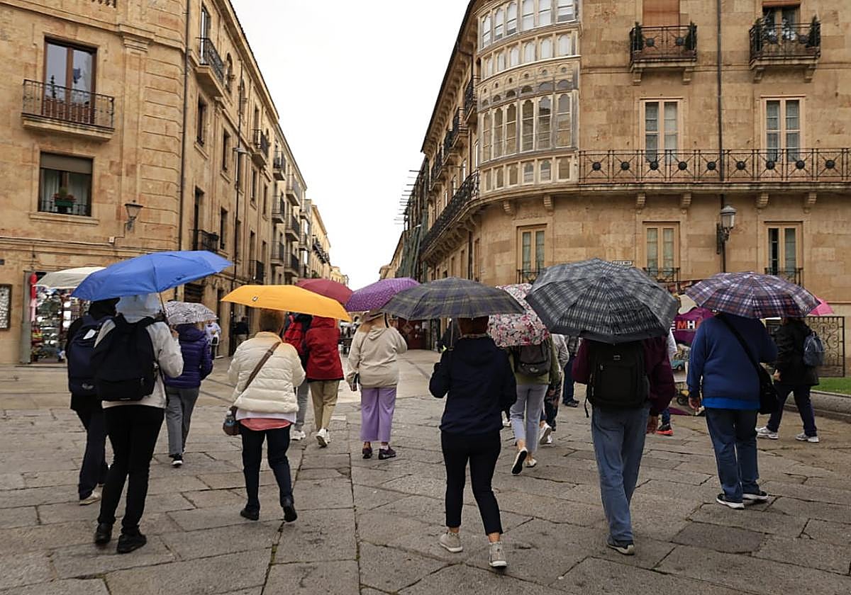 Varios turistas pasean hoy por la zona monumental de Salamanca con sus paraguas.