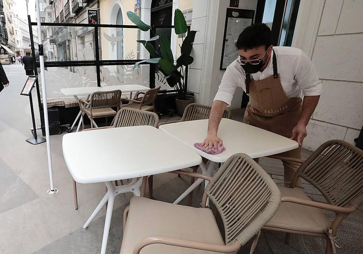 Un camarero limpia las mesas de calima.