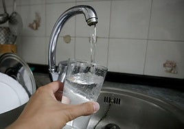 Una persona llena un vaso de agua en un grifo de una vivienda en Salamanca.