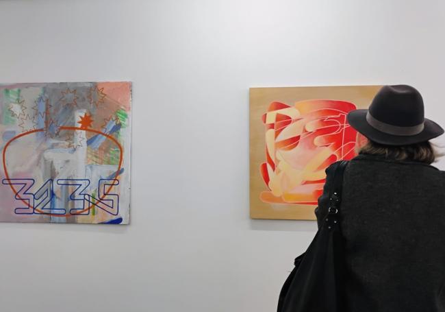 Mujer frente a dos de las obras en la exposición 'Scroll' de Marcos Tapia González.