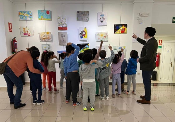 Varios niños contemplan distintos dibujos en el Espacio Joven.