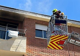 Dos bomberos se dirigen este sábado en una escalera a la vivienda incendiada en Santa Marta de Tormes.