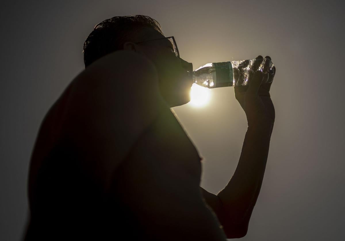 Una persona bebe agua en una calurosa tarde en una imagen de archivo.