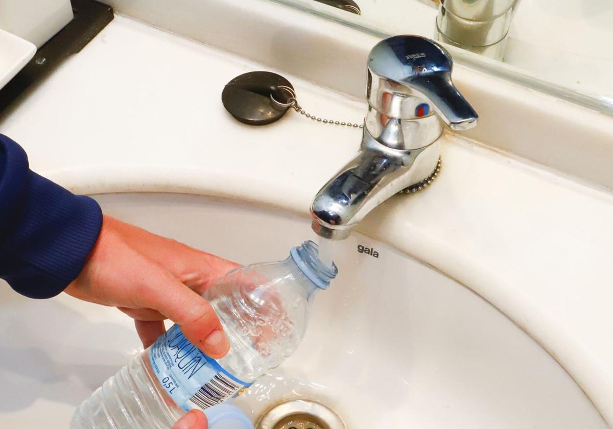 Una persona recoge agua del grifo en una botella.