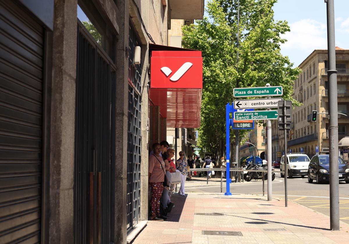 Personas se protegen del sol esperando al autobus en la Gran Vía