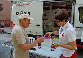 Una voluntaria de Cruz Roja reparto agua a un ciudadano.