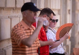 Un hombre bebe agua y una mujer se abanica.