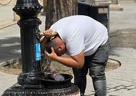 Un hombre se refresca en una fuente.