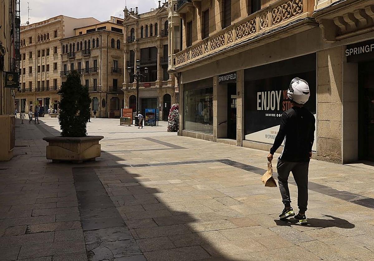 Un repartidor de comida pasea por una céntrica calle de Salamanca en un día de mucho calor.