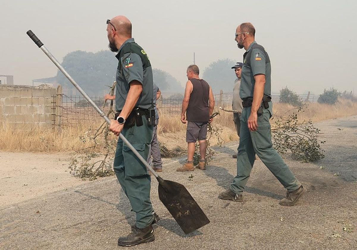 Dos guardia civiles ayudan a los vecinos en el incendio de Cipérez este viernes.