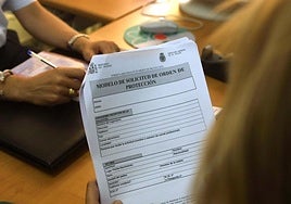 Una mujer rellena un impreso del modelo de Solicitud de orden de protección para mujeres maltratadas, en una comisaría.