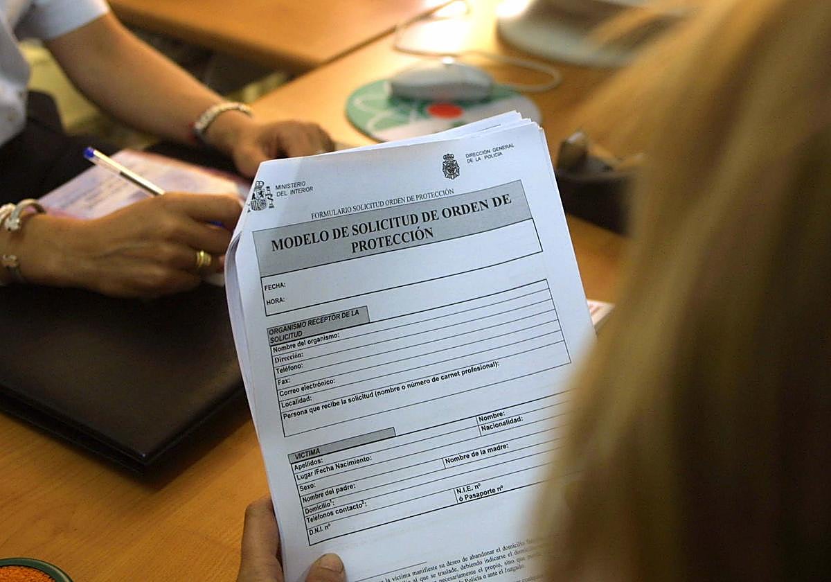 Una mujer rellena un impreso del modelo de Solicitud de orden de protección para mujeres maltratadas, en una comisaría.