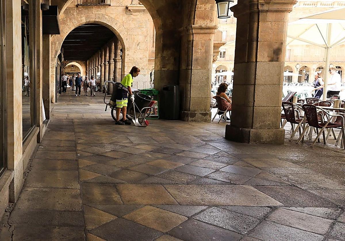 Imagen de una mujer barriendo los soportales de la Plaza Mayor de Salamanca.