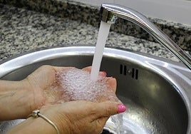 Una mujer se llena las manos con agua del grifo.