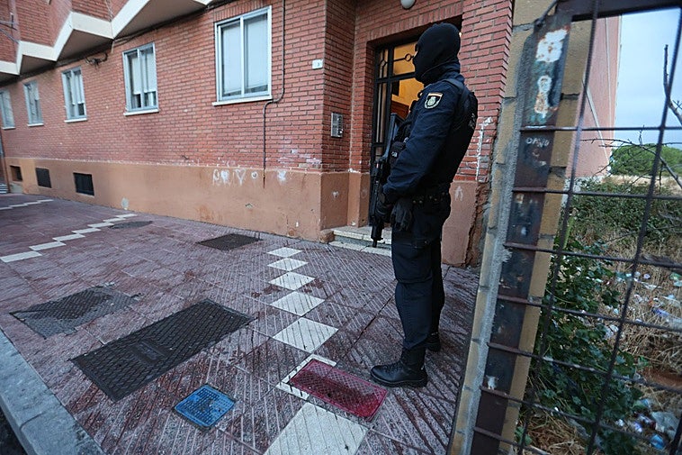 Un agente de la Policía Nacional armado frente a un portal.
