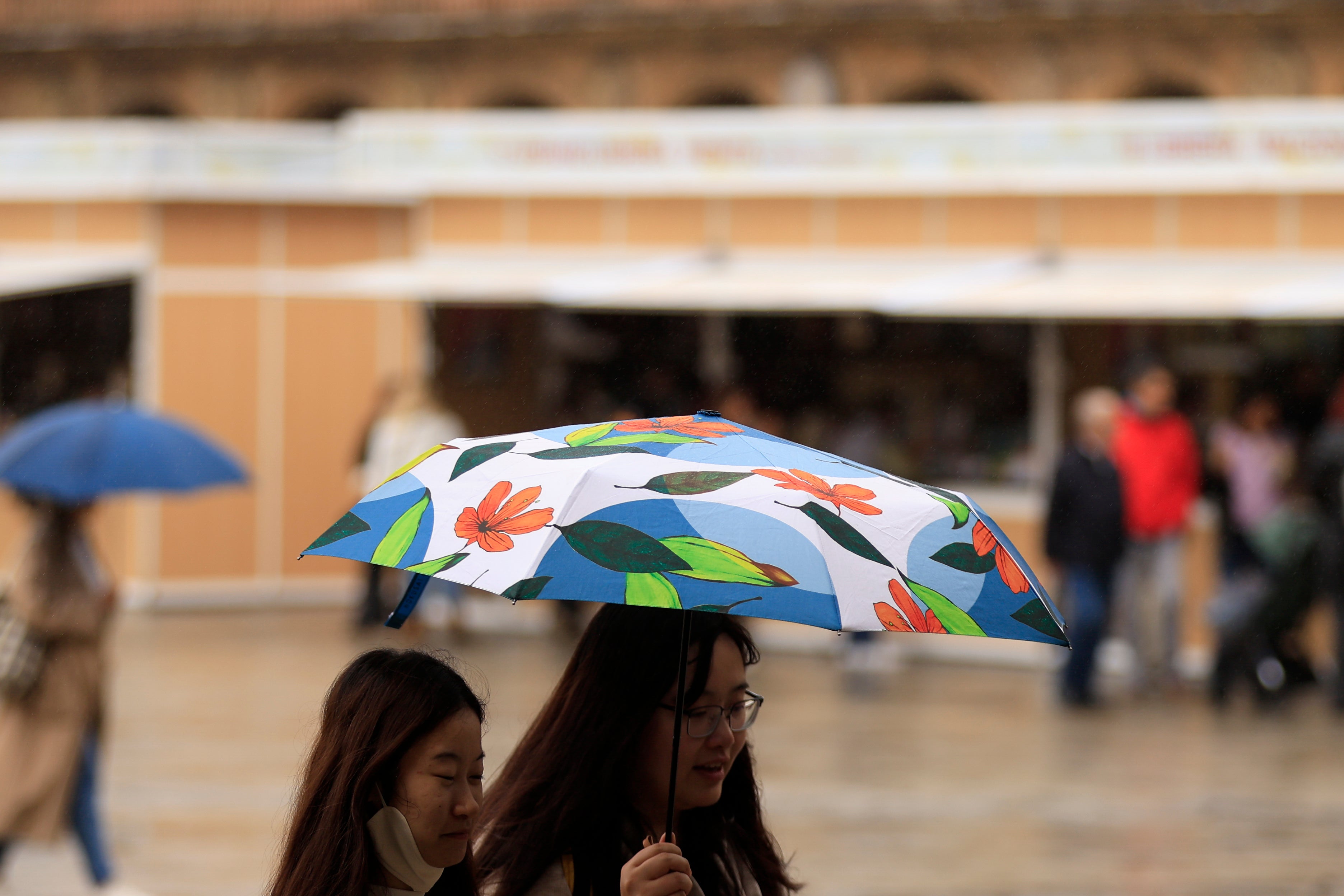 Dos turistas se protegen de la lluvia con un paraguas
