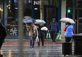 Varias personas cruzan un paso de peatones en Salamanca un día de lluvia.
