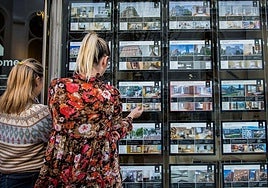 Dos mujeres observan ofertas de pisos en una inmobiliaria.