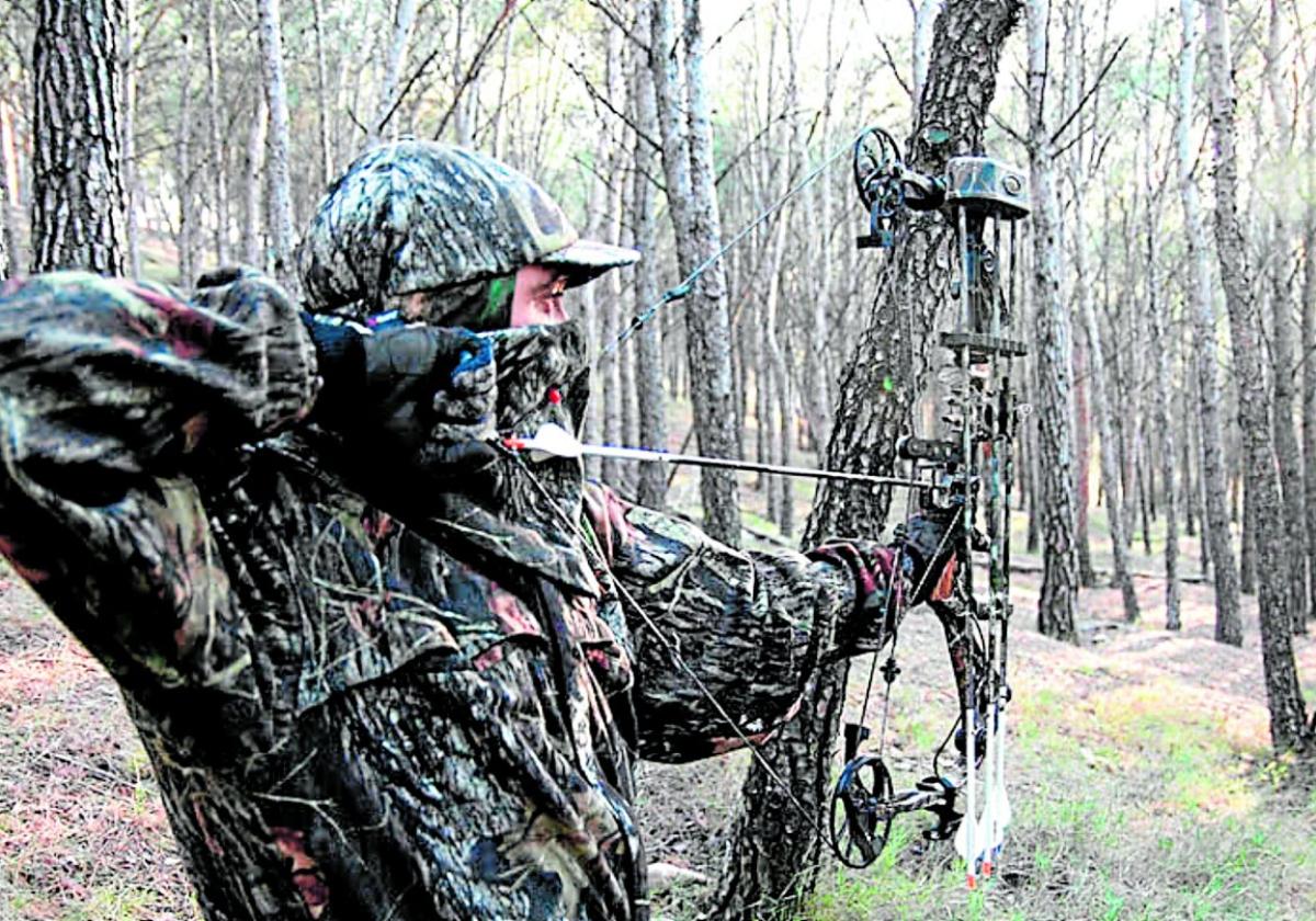 Ein Jäger in Tarnkleidung bei der Vorbereitung zum Abschuss eines Pfeils.