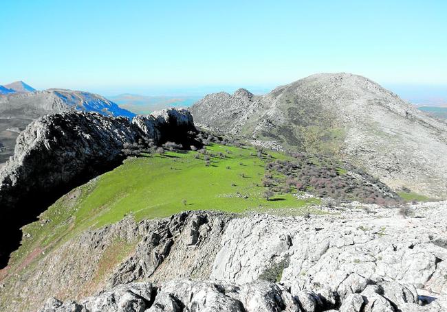 Eine grüne Wiese zwischen Kalksteinfelsen belohnt diejenigen, die diese schroffe Berglandschaft durchwandern
