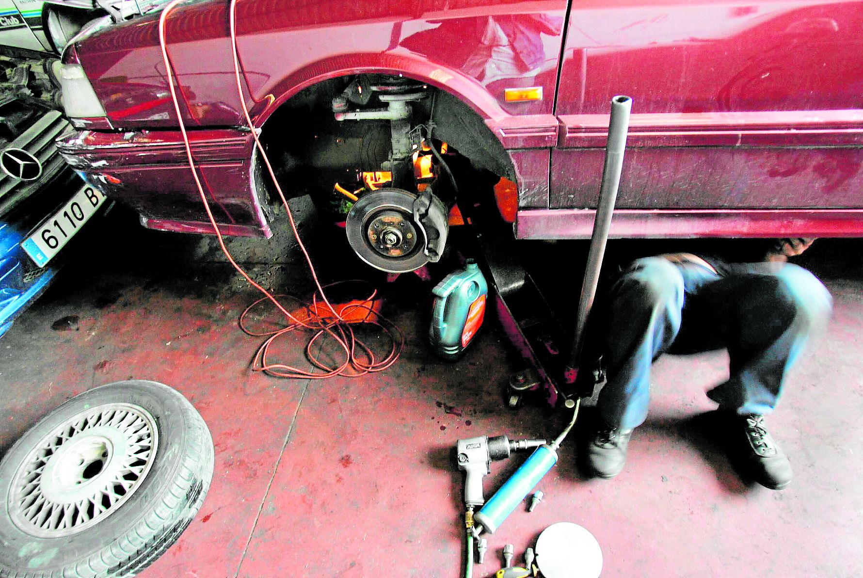 Ein Kfz-Mechaniker bei der Reparatur an einem Auto.
